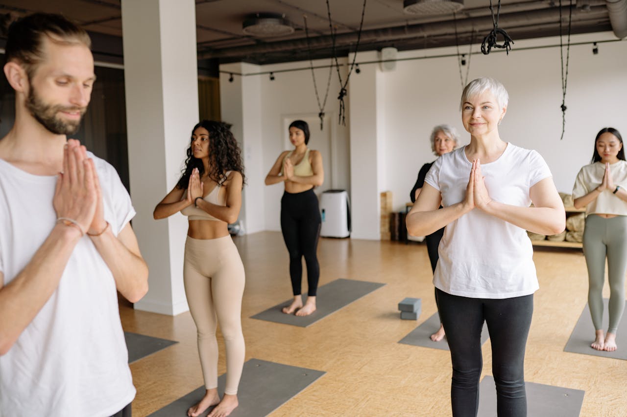 A group of diverse adults meditating and performing yoga in a studio.